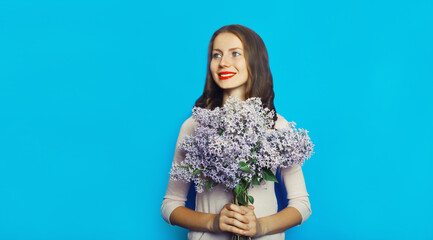 Portrait of happy smiling woman with bouquet of flowers on blue background