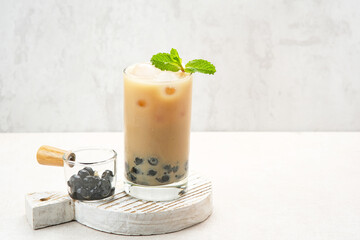 Boba milk tea with brown sugar syrup in a tall glass with ice and mint leaf
