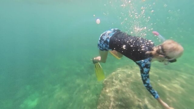 Snorkeler dives near vibrant coral formations in clear tropical waters on Chinese wreck dive site in Oman in Mirbat town of Dhofar region.