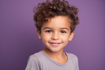 Portrait of a cute little boy with curly hair on purple background