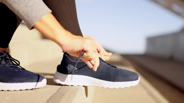 Video close-up of an unrecognizable mature woman tying her shoes to run