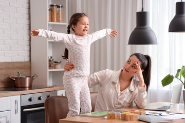 Working mother with her naughty little daughter in kitchen