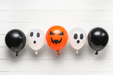 Different funny Halloween balloons on white wooden background