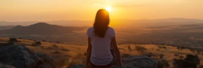 Foto op Aluminium Woman sitting on a rock overlooking a vast landscape at sunset. © Alena