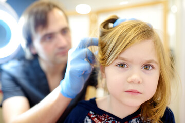 Close-up portrait of little girl during appointment of dermatologist in modern clinic. Doctor...