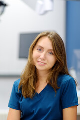 Vertical portrait of female ENT doctor during appointment of patient in medical office. Professional otolaryngologist is on workplace. Beautiful woman looking at camera