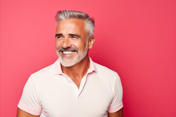 Handsome middle-aged man in polo shirt on pink background