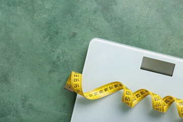 Scales with yellow measuring tape on green background