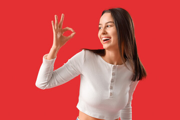 Young woman showing OK on red background