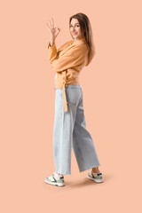 Young woman showing OK on brown background