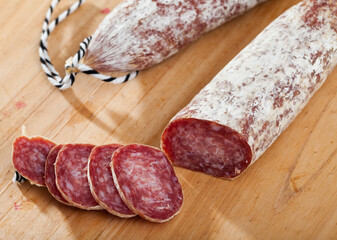 Catalan sort of popular Spanish Longaniza sausage from minced pork with cut slices on wooden...