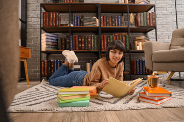 Young woman reading book on floor in library - Powered by Adobe