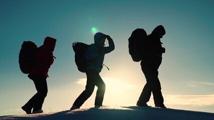 Silhouette of group of tourists, travelers, extending helping hand to each other, climbing snowy...