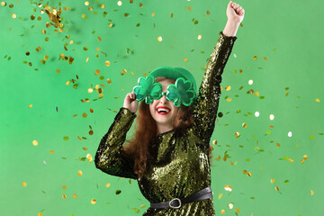 Young woman in eyeglasses with confetti on green background. St. Patrick's Day celebration