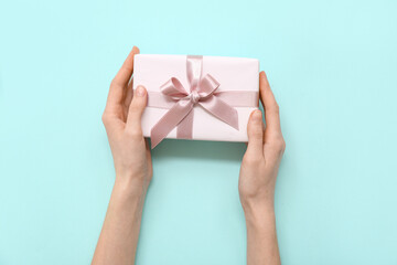 Female hands with gift box on blue background. International Women's Day