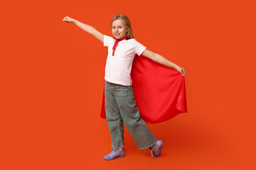 Cute teenage girl dressed as superhero on orange background