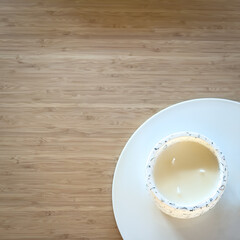 Top view of a white candle on a ceramic plate on a wooden table with copy space - 745466081