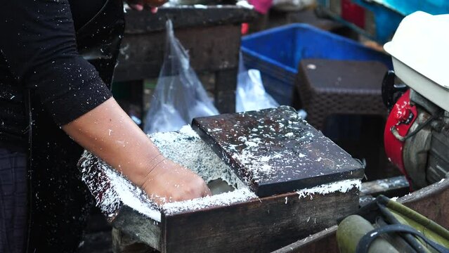 grating coconut using a machine is done by Indonesian women