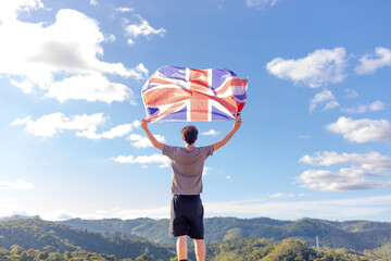 British man standing atop a mountain, proudly holding the British flag. Showcasing British...