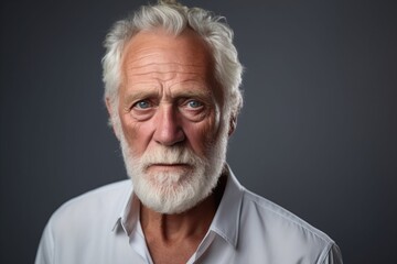 Portrait of a senior man with white beard against grey background.
