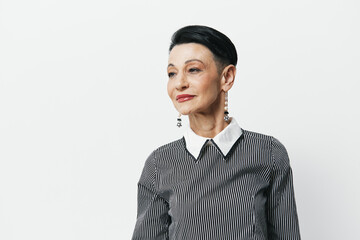 Portrait of an elegant senior woman in a stylish black and white striped shirt against a plain...