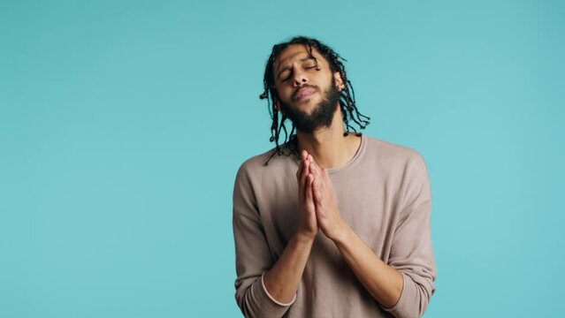 Desperate guy asking for forgiveness, putting hands together in imploring gesturing, showing regret emotion. Upset man saying sorry, begging for apology, feeling guilty, studio background, camera A