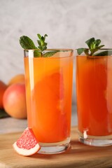 Tasty freshly made grapefruit juice, fruit and mint on table, closeup