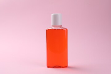 Fresh mouthwash in bottle on pink background