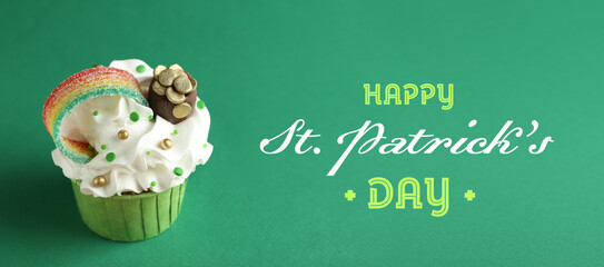 Happy St. Patrick's day card. Tasty cupcake with sour rainbow belt and pot of gold toppers on green...