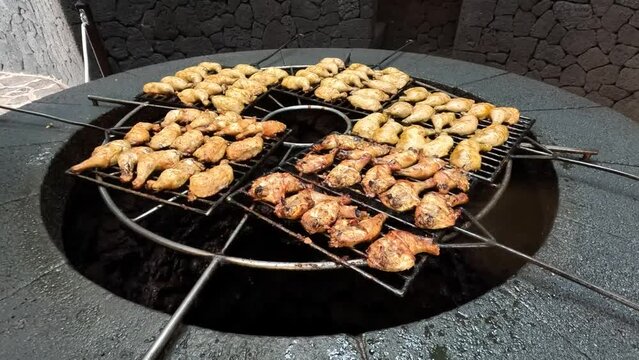 Large amount of chicken legs on huge volcano heated grill located at Timanvaya Natural Park Lanzarote Spain which is a popular tourist attraction and destination to travel to 4k high resolution