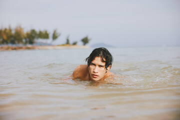Swim, Splash, and Smile: Asian Man enjoying a Tropical Beach Vacation in the Blue Ocean