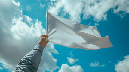 Arm Holding a Fluttering White Sheet Against a Blue Sky