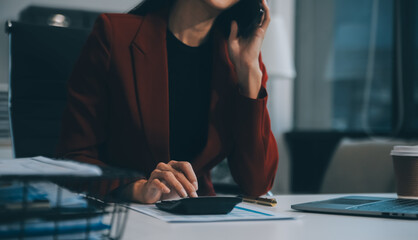 Asian Businesswoman Using laptop computer and working at office with calculator document on desk,...