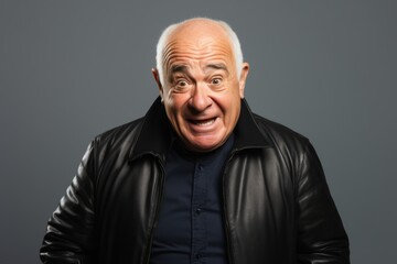 senior man with leather jacket and surprised facial expression on grey background