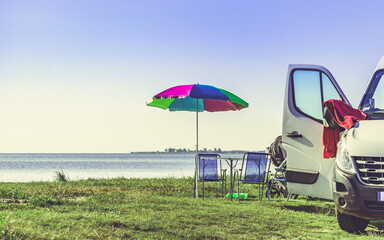 Umbrella with chairs at campervan on beach