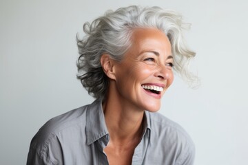 Close up portrait of a happy senior woman laughing against grey background.