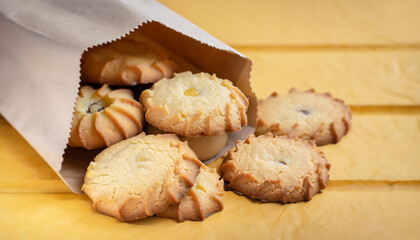 A group of butter shortbread cookies on craft paper bag on wooden yellow box background. Selective focus. Close up.