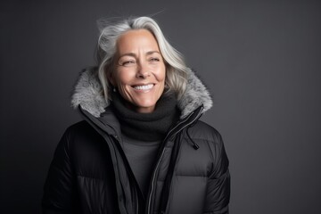 Portrait of a happy senior woman in winter jacket on a dark background