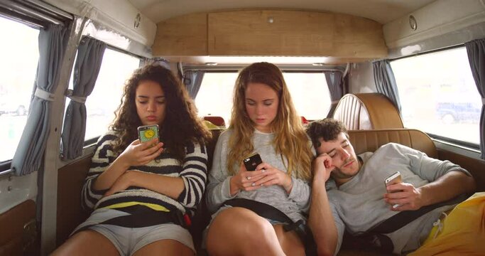 Friends, road trip and phone in van for vacation, texting and relax for driving, transport and web blog. Gen z people, women and man with smartphone, travel and reading on mobile app for social media