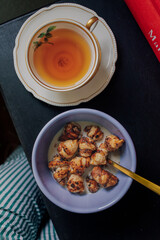 mini croissant cereal and cup of tea on black table with hint of green striped pajamas 