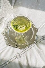 chartreuse green cocktail in coupe glass with sparkling silver background, chartreuse, sparkling,...