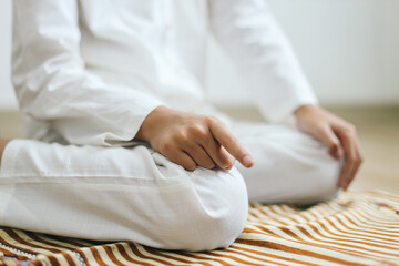 Close up of muslim man doing salat with Tahiyat posing on the prayer mat. Muslim showing index...