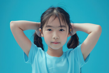 young fitness Asian athletic sport little girl doing sport, showing strength gesture with arms, blue background