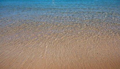 Beach with golden sand, turquoise ocean water. Panoramic sea view. Natural background for summer vacation.