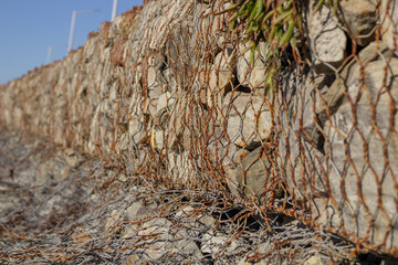 side view of stone wall contained by metal mesh