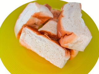 a pile of bread on a yellow plastic plate, isolated on a white background, concept of hunger, poverty and inflation impacting society or humans.