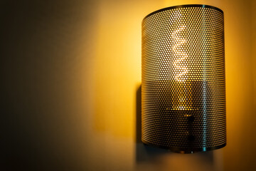 Lamp on the wall with metal grid protection and incandescent bulb