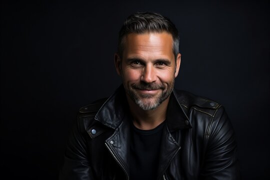 Portrait of a handsome man in a leather jacket on a dark background