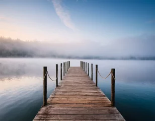 Foto op Plexiglas Wooden pier by lake at calm foggy morning. © orelphoto