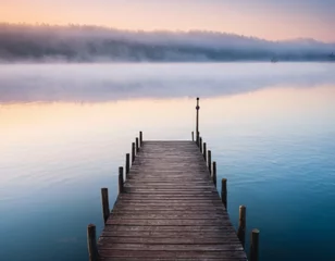 Küchenrückwand glas motiv Wooden pier by lake at calm foggy morning. © orelphoto